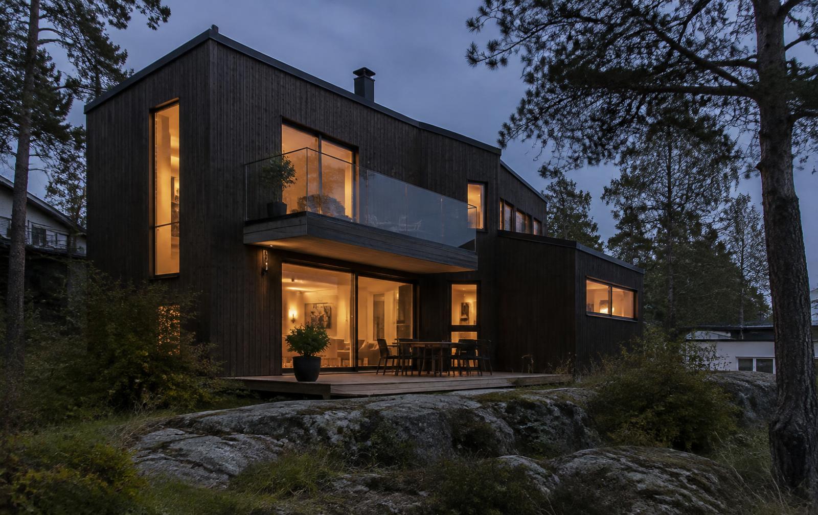Moderne bolig med mørk trekledning i skumringen (illustrasjon)